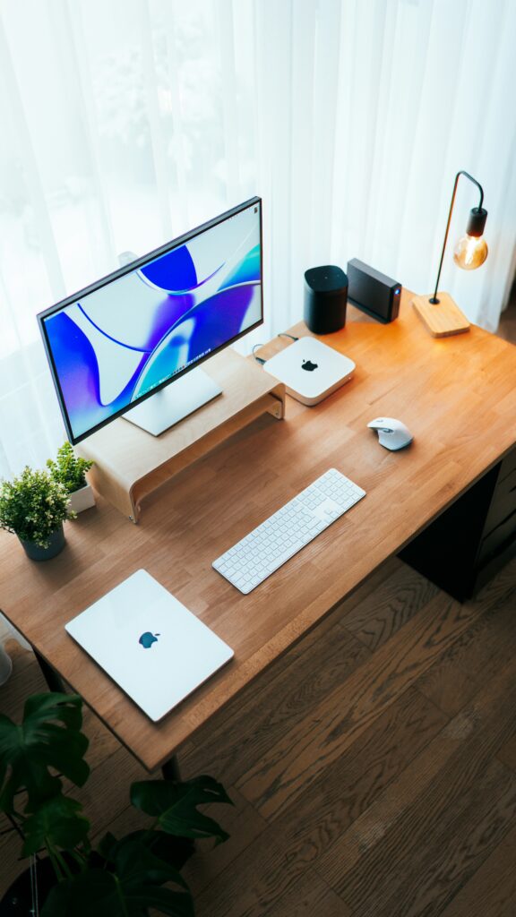 Laptop raised on a simple wooden stand with external keyboard and mouse on a desk
